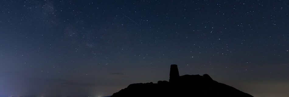 A nightscape of a starry sky and a shooting star from Black Fell in the Lake District.