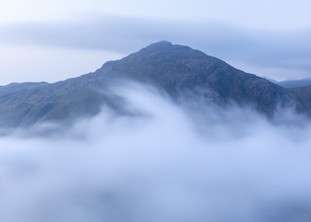 Landscape photograph of Pike of Blisco surrounded by a blanket of cloud as a temperature inversion builds during blue hour in the Lake District.