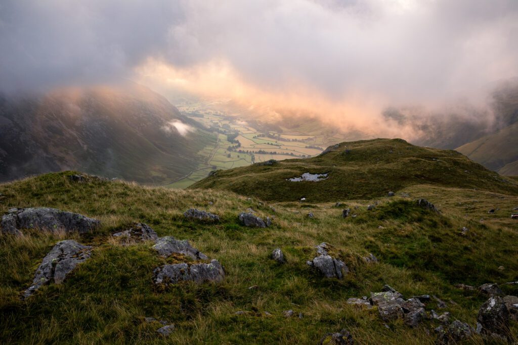 Summer landscape photography from Bowfell in the Lake District during a breathtaking summer morning. Low cloud hovers above Mickleden Valley catching the glorious sunrise light around Great Langdale.