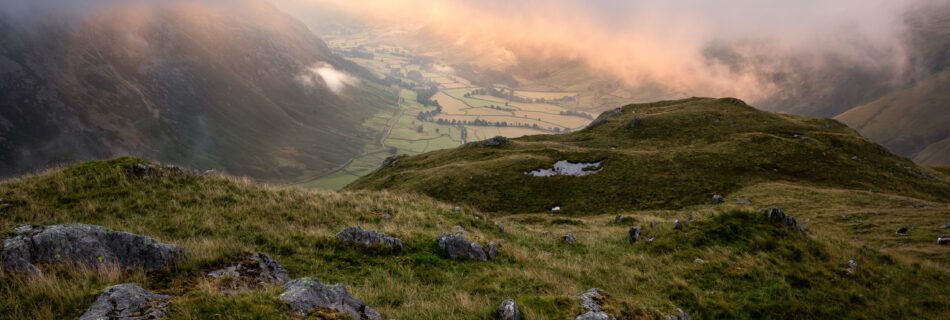 Summer landscape photography from Bowfell in the Lake District during a breathtaking summer morning. Low cloud hovers above Mickleden Valley catching the glorious sunrise light around Great Langdale.