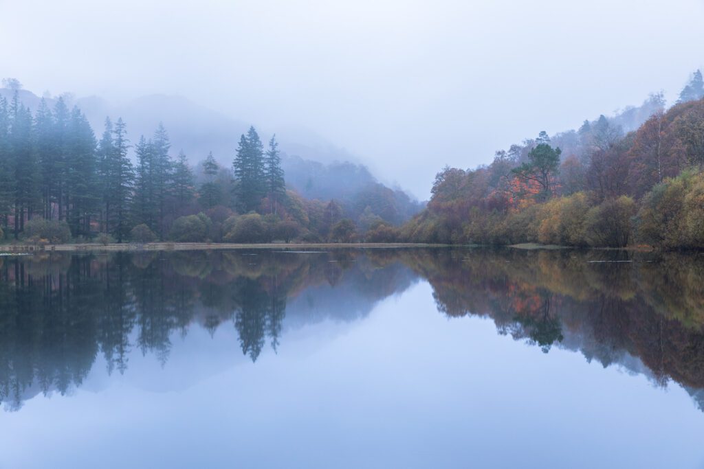 Beautiful autumn reflections across Yew Tree Tarn near Coniston in the early hours of the morning.