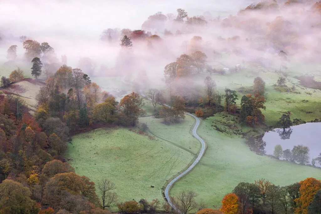 A classic landscape photograph from Loughrigg Fell in the Lake District on a misty autumn morning.