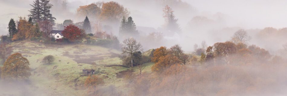 A Lake District autumnal landscape covered in mist during sunrise on Loughrigg Fell.