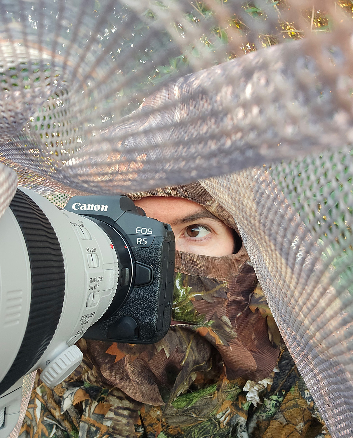 Simon Evans, with his camera and dressed in 3D camouflage, under a makeshift hide made for photographing a local Barn Owl.