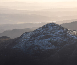 Landscape photograph of Pike O'Blisco in the Lake District surrounded by delicate layers of mountains in the distance captured from Bowfell.
