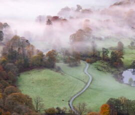 A classical Lake District view of the winding road from Loughrigg Fell during a misty autumnal morning.