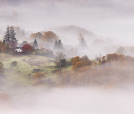 A Lake District autumnal landscape covered in mist during sunrise on Loughrigg Fell.