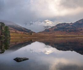A dramatic winter sunrise at Blea Tarn with a snow-covered Langdale Pikes in the distance.
